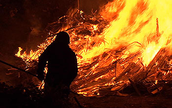 Firefighter silhouetted against blazing hillside