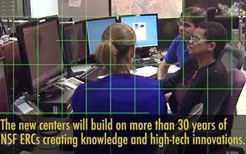 Three people facing several monitors.