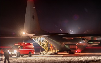 An ambulance next to a large military plane