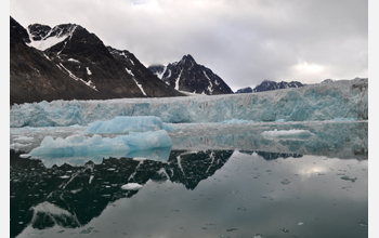 A glacier calving icebergs into a fjord in the Norwegian archipelago of Svalbard, Norway