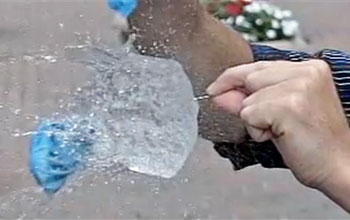 Close up image of a water balloon being popped with a needle