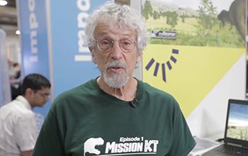 man in a green shirt standing next to laptops