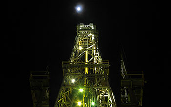 Moonlight and manmade light illuminate drilling derrick on drillship <em>JOIDES Resolution</em>