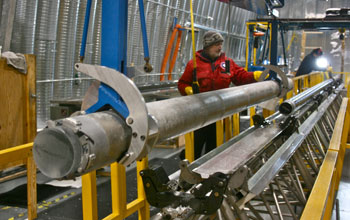 Man standing next to a West Antarctic ice core barrel, at the site.