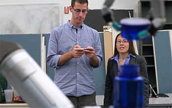 Two people watching a robot perform a task