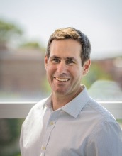 Man in a white shirt smiling at the camera