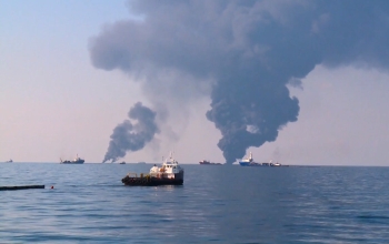 ships on the ocean with smoke on the horizon