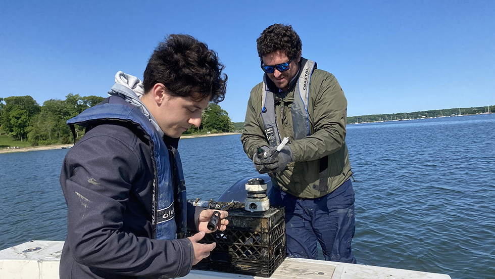 Assistant professor and graduate student aboard vessel collecting samples in Long Island's Cold Sprint Harbor