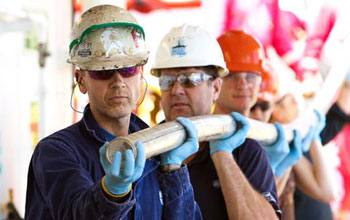 Photo of shipboard scientists carrying a core from volcanoes in the Louisville Seamount Trail.