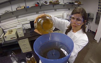 Photo of woman pouring dirty looking water into a bucket containing a filter