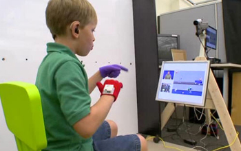 Photo of a child signing as he watches video instruction