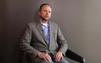 man sitting on a chair against a plain background